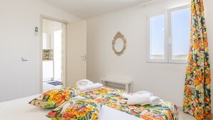 A hotel room with a bed, a bedside table, a mirror, and a window with curtains.