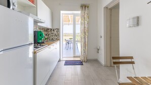 A kitchen with a refrigerator, stove, and cabinets, leading to a dining area with a table and chairs.
