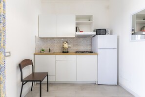 A compact kitchen with white cabinets, a gas stove, a microwave, and a refrigerator. - Apartment "Fenicottero Rosa" with Private Terrace & Wi-Fi (Granelli)