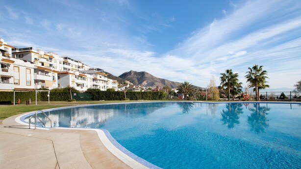 A swimming pool with a mountain in the background, surrounded by buildings.