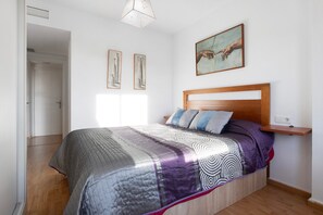 Une chambre à coucher avec un lit en bois, une table de chevet, une étagère fixée au mur et un tableau.