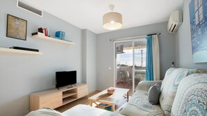 A living room with a sofa, TV, wooden shelves, and a table with a basket.