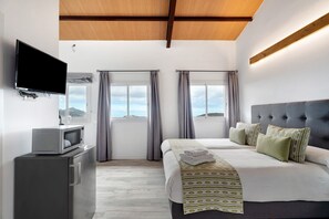 A hotel room with a bed, a television, a microwave, and a view of the mountains.