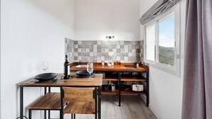 Une cuisine compacte avec un coin repas, une fenêtre avec des rideaux et un pare-feu en carreaux.