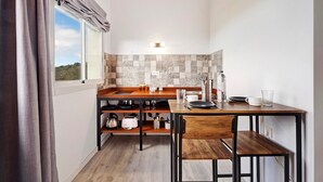 Eine kleine Küche mit Holztischplatte, eingebautem Backofen, Spüle und einem Fenster mit Vorhängen.