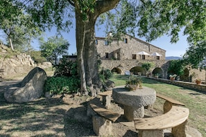 A stone building with a courtyard, stone benches, and potted plants.