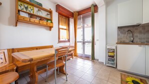 Una cocina con una mesa y sillas de madera, un estante empotrado con adornos y un piso de baldosas.