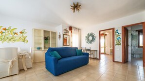 Una sala de estar con un sofá azul, una mesa de comedor y una zona de cocina.