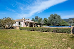A house with a patio, a swimming pool, and a well-maintained lawn.