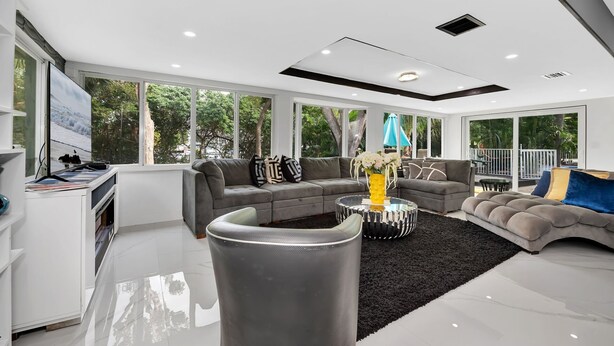 A modern living room with a grey sofa set, a coffee table, and a TV on a stand. - BEST LOCATION, Few min walk, Bike to Deerfield Beach and Pier. one acre property (Deerfield Beach)