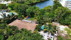 An aerial view of a property with a swimming pool, a children's play area, and lush greenery. - BEST LOCATION, Few min walk, Bike to Deerfield Beach and Pier. one acre property (Deerfield Beach)