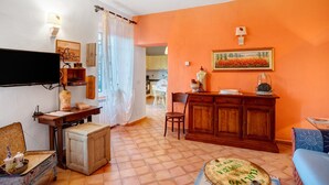 A living room with a television, a wooden cabinet, a dining table, and a chair. - Apartment 'Casa Cen' with Sea View, Private Terrace and Wi-Fi (Dolcedo)