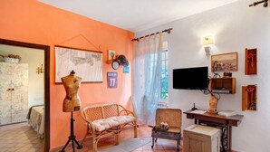 A room with a wicker sofa, a small table, a sewing machine, and a television. - Apartment 'Casa Cen' with Sea View, Private Terrace and Wi-Fi (Dolcedo)