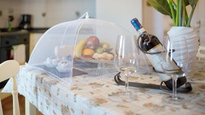 A table with a floral tablecloth, a covered fruit display, a wine bottle, and a vase with flowers. - Apartment 'Casa Cen' with Sea View, Private Terrace and Wi-Fi (Dolcedo)