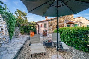 Une terrasse avec deux chaises longues, une table et un parasol.