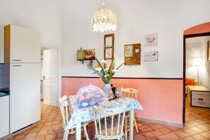 Een keuken met een eettafel, stoelen, een kroonluchter en wanddecoraties.