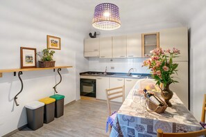 Una cocina compacta con una mesa de comedor, una lámpara colgante y un florero con flores.