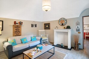 Una sala de estar con sofá, mesa de centro, chimenea y objetos decorativos.