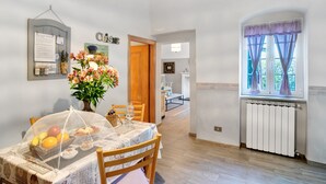 Un coin repas avec une table dressée pour deux personnes, un vase de fleurs et un tableau de menu fixé au mur.