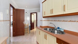 Cocina con dos fregaderos, armarios de madera y salpicadero de azulejos.