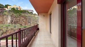 Un balcón con vistas a una ladera rocosa y un edificio al fondo.