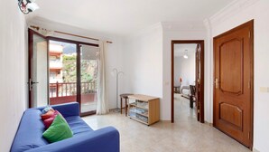 Una habitación con un sofá azul, un armario de madera y una puerta que da a otra estancia.