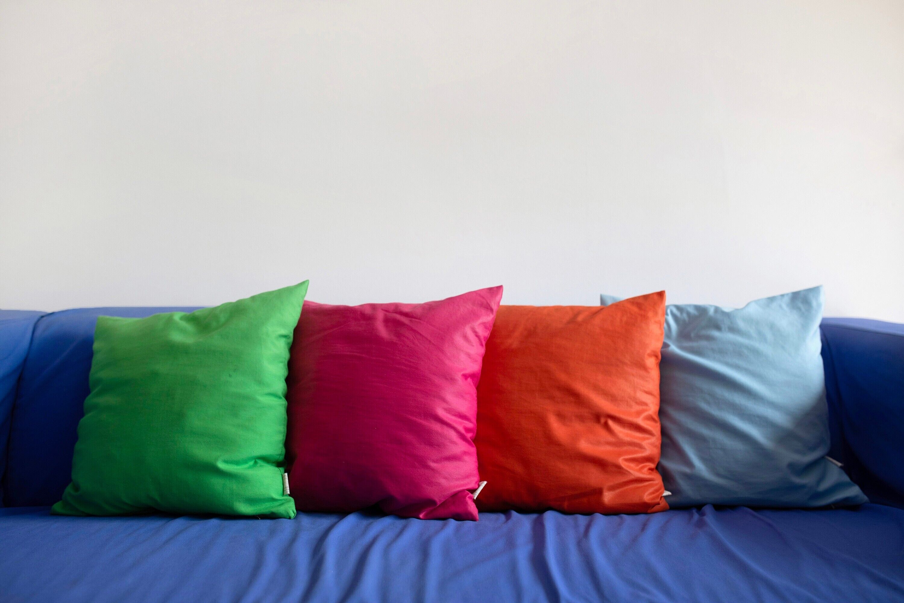Un sofá azul con cuatro almohadones de colores.