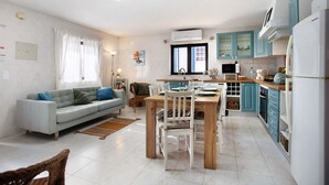 A modern kitchen with a dining area, a sofa, and a television.