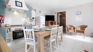A kitchen with white cabinets, a wooden dining table, and white chairs.