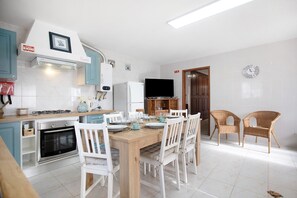 A kitchen with white cabinets, a wooden dining table, and white chairs.