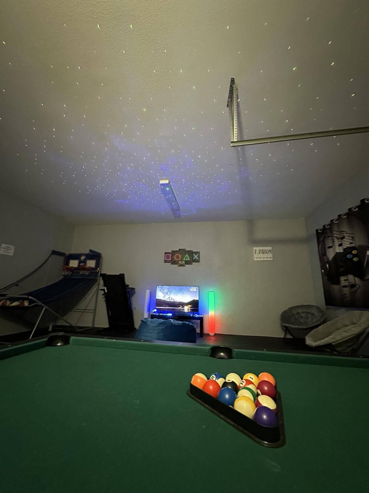 Quarto com mesa de bilhar, televisão e projetor no teto.