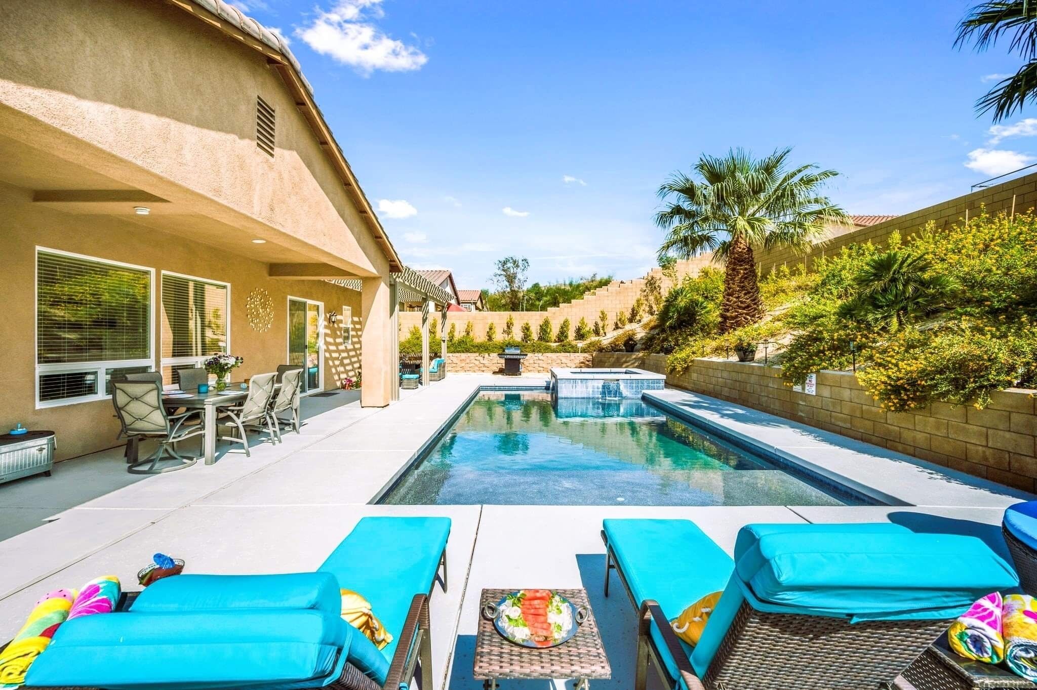 A swimming pool with lounge chairs and a dining area.