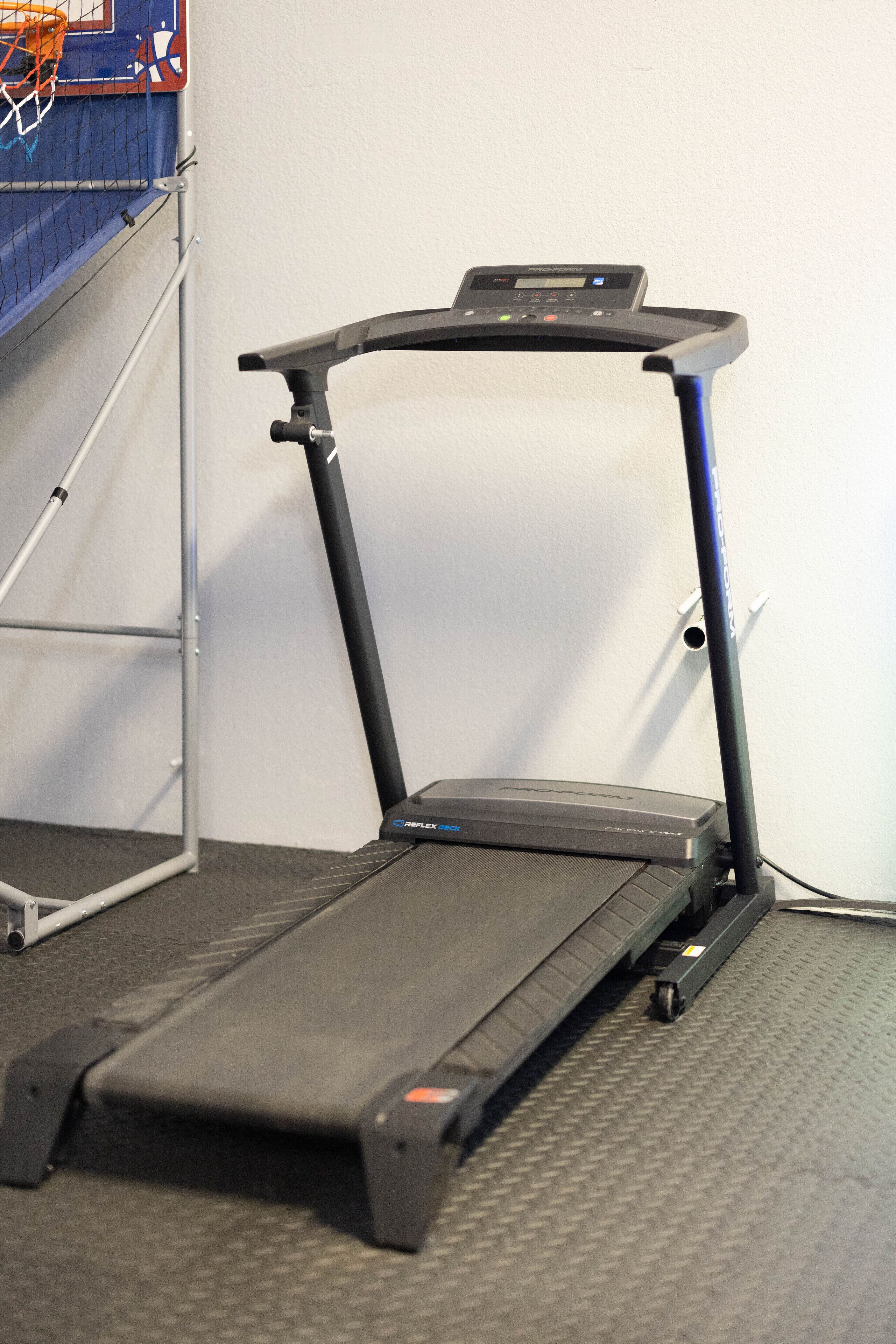 A treadmill in a room with a grey floor and a white wall.