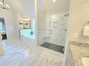Enjoy a refreshing shower or soak in the bathtub, both with marble tile flooring.