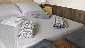 A neatly made bed with pillows, a folded blanket, and a bedside table with a lamp.