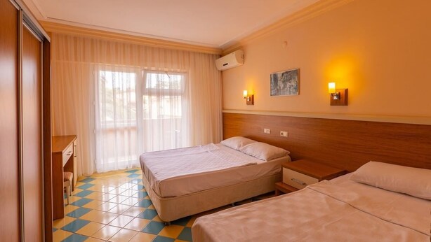 A hotel room with two beds, a wooden headboard, a desk, and a window with sheer curtains. - Dream Holiday Resort  (Burhaniye)