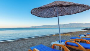 A beach with rows of sun loungers and a large woven umbrella. - Dream Holiday Resort  (Burhaniye)