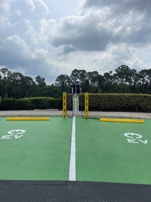 A green EV charging station with a white line marking the parking space. - 4BR Resort Home, 2 King Suites. Disney 9 min. Pools/Tennis/Pickleball/Gym/Sauna (Kissimmee)