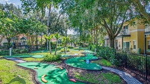 A miniature golf course with green fairways and red obstacles, surrounded by trees and a fence. - 4BR Resort Home, 2 King Suites. Disney 9 min. Pools/Tennis/Pickleball/Gym/Sauna (Kissimmee)