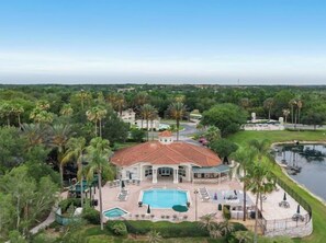 A large house with a swimming pool, surrounded by palm trees and a body of water.