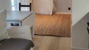 Ein modernes, kompaktes Zimmer mit Bett, einem kleinen Tisch und einem Sessel.