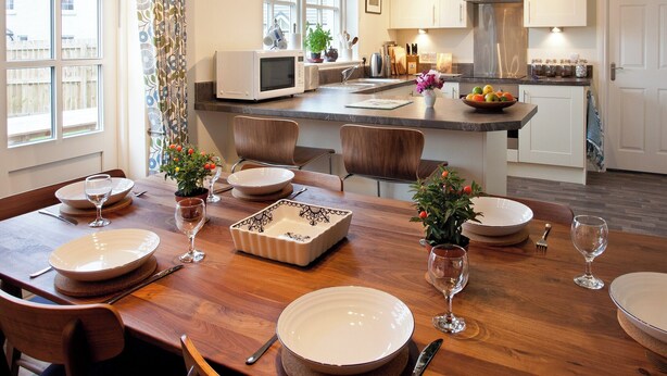A modern kitchen with white cabinets, a microwave, and a stainless steel range hood. - Mackay Road - UK7451 (Dornoch)