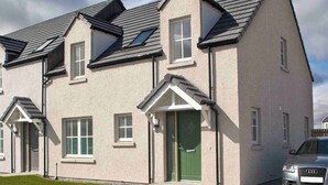 A modern two-story residential building with a symmetrical facade, multiple windows, and a green door. - Mackay Road - UK7451 (Dornoch)