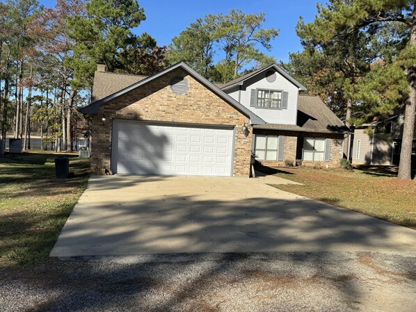 A two-story house with a garage, a brick exterior, and a lawn.