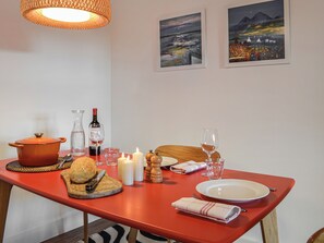A dining table set with a bread roll, a knife, a wine bottle, glasses, candles, and a plate.