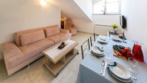 A modern living room with a sofa, a coffee table, and a dining area set for a meal.