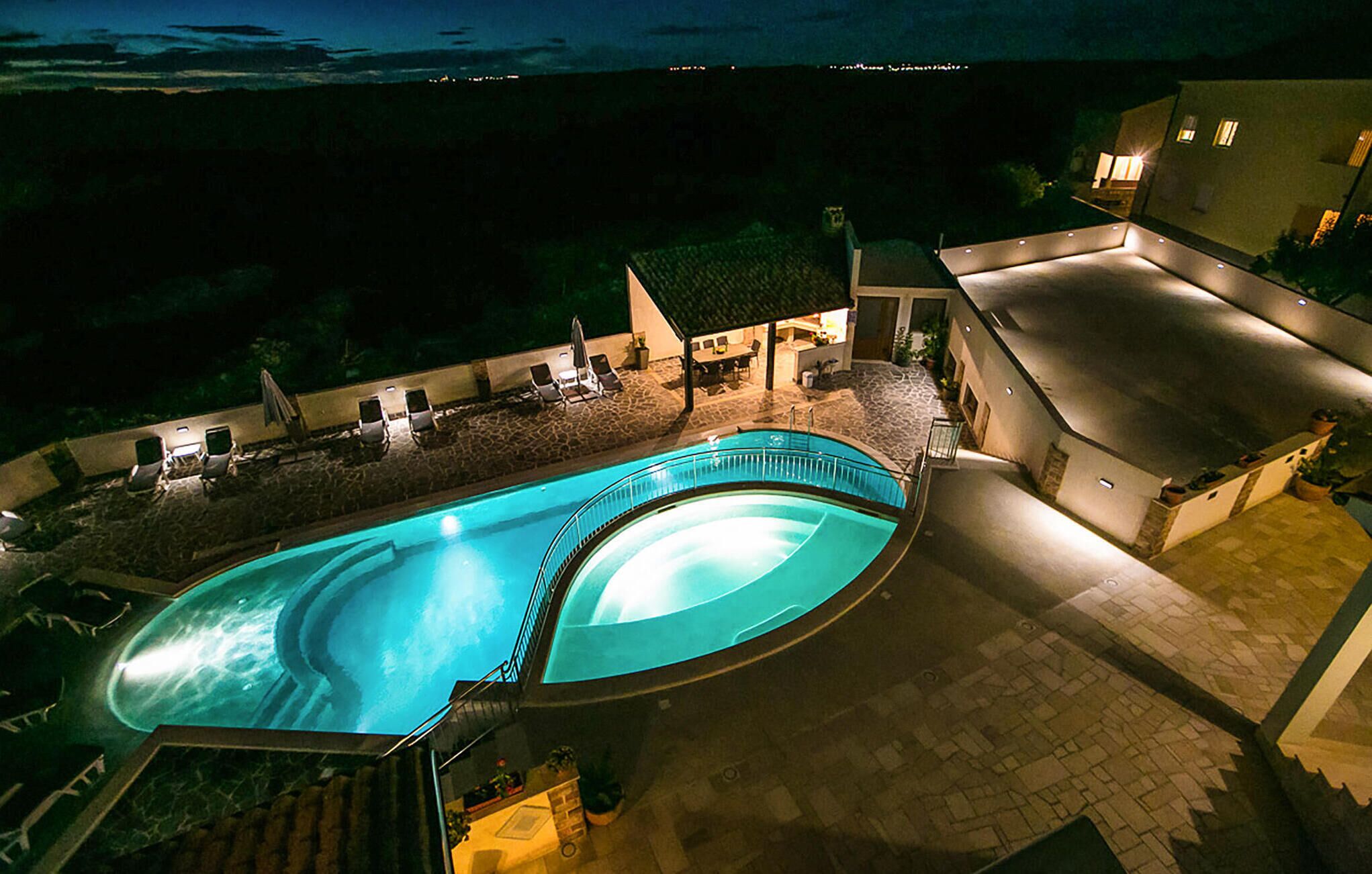 A swimming pool with a curved design, surrounded by lounge chairs and a covered seating area.
