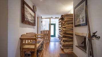 Ein Flur mit Holzbänken, einem Holzstoß und gerahmten Bildern an den Wänden.