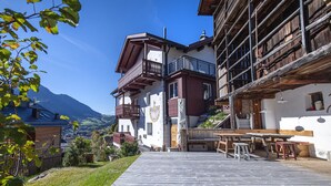 Un chalet traditionnel doté d’une terrasse en bois, d’un espace salon extérieur et offrant une vue sur les montagnes.