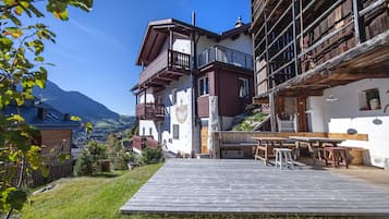 Ein traditionelles Chalet mit Holzterrasse, Sitzgelegenheit im Freien und Bergblick.
